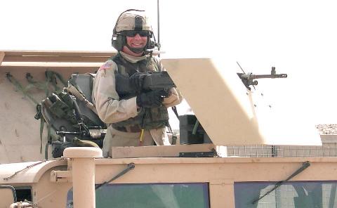 Photograph of an American soldier manning a machine gun on his Humve in Iraq, taken by an American soldier taken by an American soldier of C Co, 1/252 Army Reserve Battalion.  Logo for the M203.com presentation entitled Warrior.